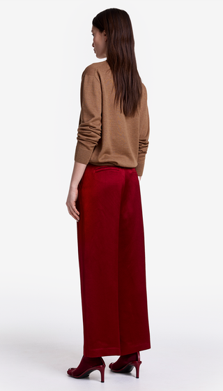 Woman wearing a brown top and red pants on a white background