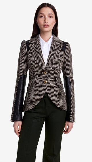 Woman wearing a patterned blazer with leather sleeves on a white background