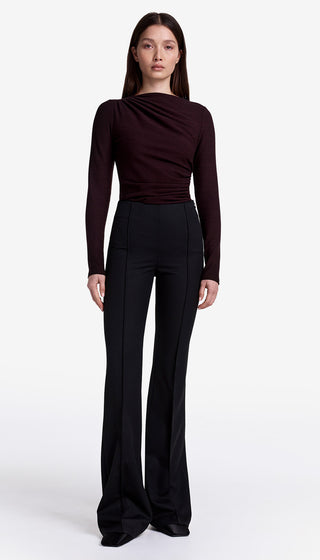 Woman wearing a dark long-sleeve top and black wide-leg pants on a white background
