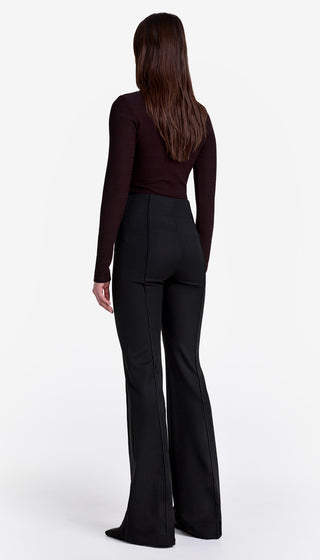 Person wearing black flared pants and a dark top on a white background
