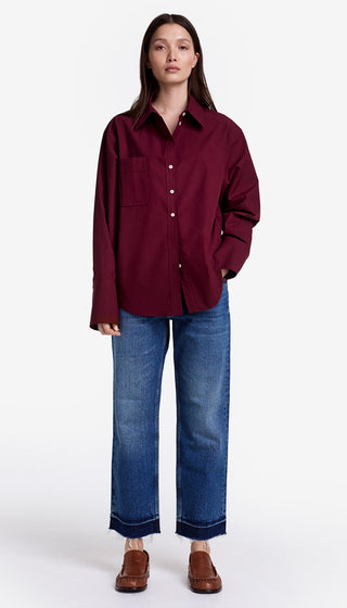 Person wearing a burgundy shirt and blue jeans on a white background
