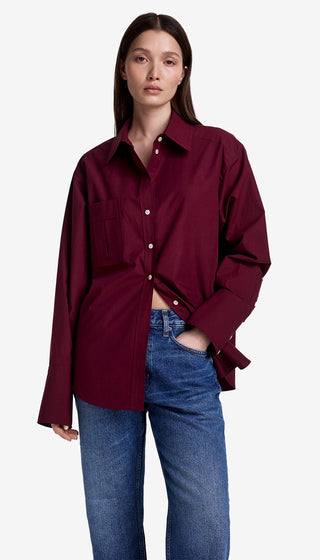 Person wearing a burgundy shirt and blue jeans on a white background