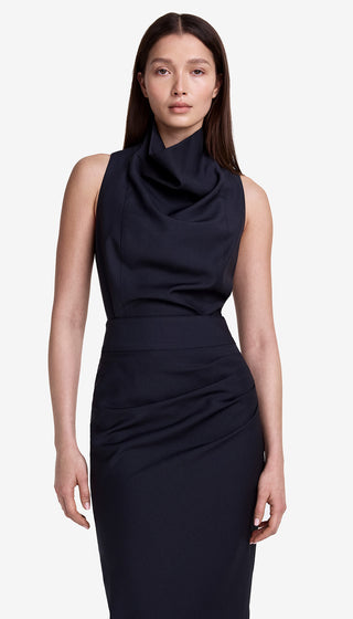 Woman wearing a navy sleeveless dress against a white background