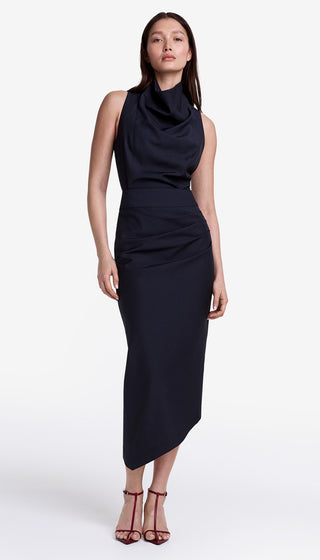 Woman wearing a black sleeveless dress with a draped design on a white background