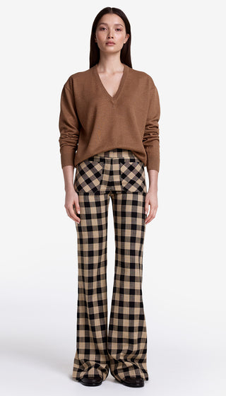 Woman wearing a brown sweater and plaid pants on a white background