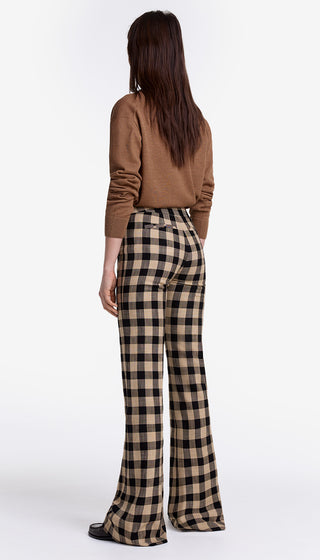 Person wearing a brown top and plaid pants on a white background