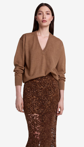 Woman wearing a brown sweater and lace skirt on a white background