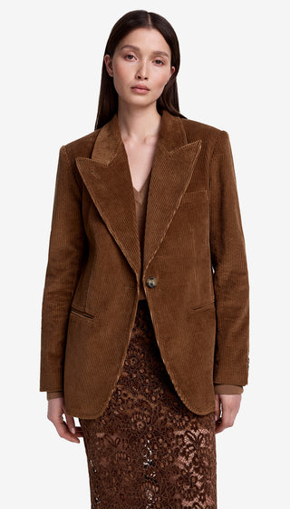 Woman wearing a brown corduroy blazer over a patterned dress on a white background