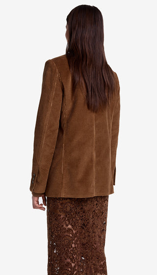 Person wearing a brown jacket and patterned pants on a white background