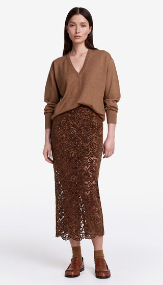Woman wearing a brown sweater and lace skirt on a white background