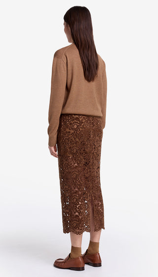 Woman wearing a brown sweater and patterned skirt on a white background