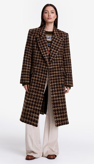 Woman wearing a long houndstooth pattern coat on a white background
