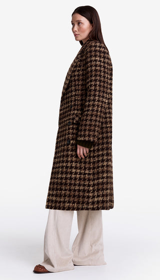 Person wearing a brown houndstooth patterned coat on a white background