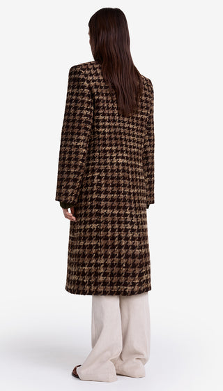Person wearing a long houndstooth pattern coat on a white background