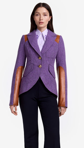 Woman wearing a purple blazer with brown leather sleeves on a white background