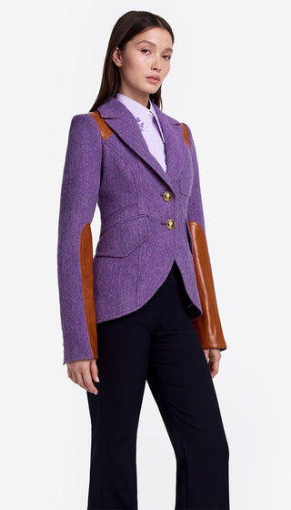 Woman wearing a purple blazer with brown leather accents on a white background