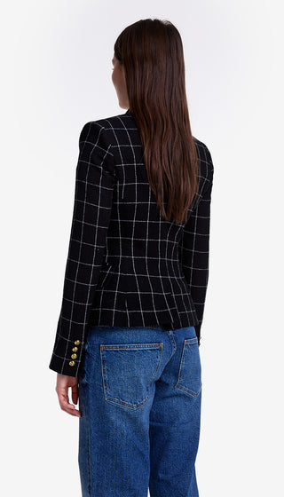 Person wearing a black checkered blazer and blue jeans on a white background