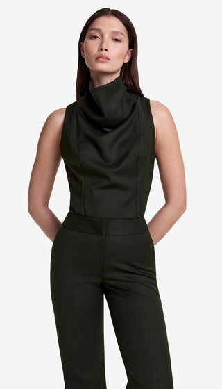 Woman wearing a black sleeveless top with a draped design and matching pants on a white background