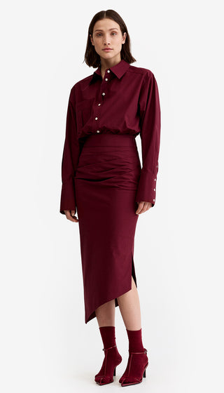 Woman wearing a burgundy outfit with a shirt and skirt on a white background
