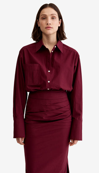 Woman wearing a burgundy shirt and skirt set on a white background