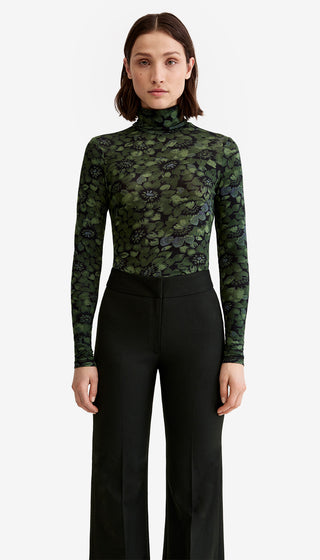Woman wearing a camouflage long-sleeve top and black pants on a white background