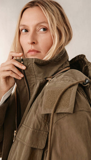 Woman wearing a brown jacket against a neutral background