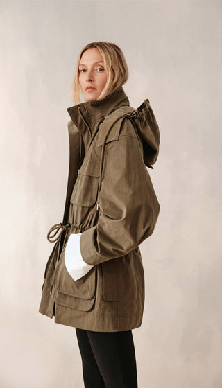 Person wearing a brown jacket with a hood on a plain background