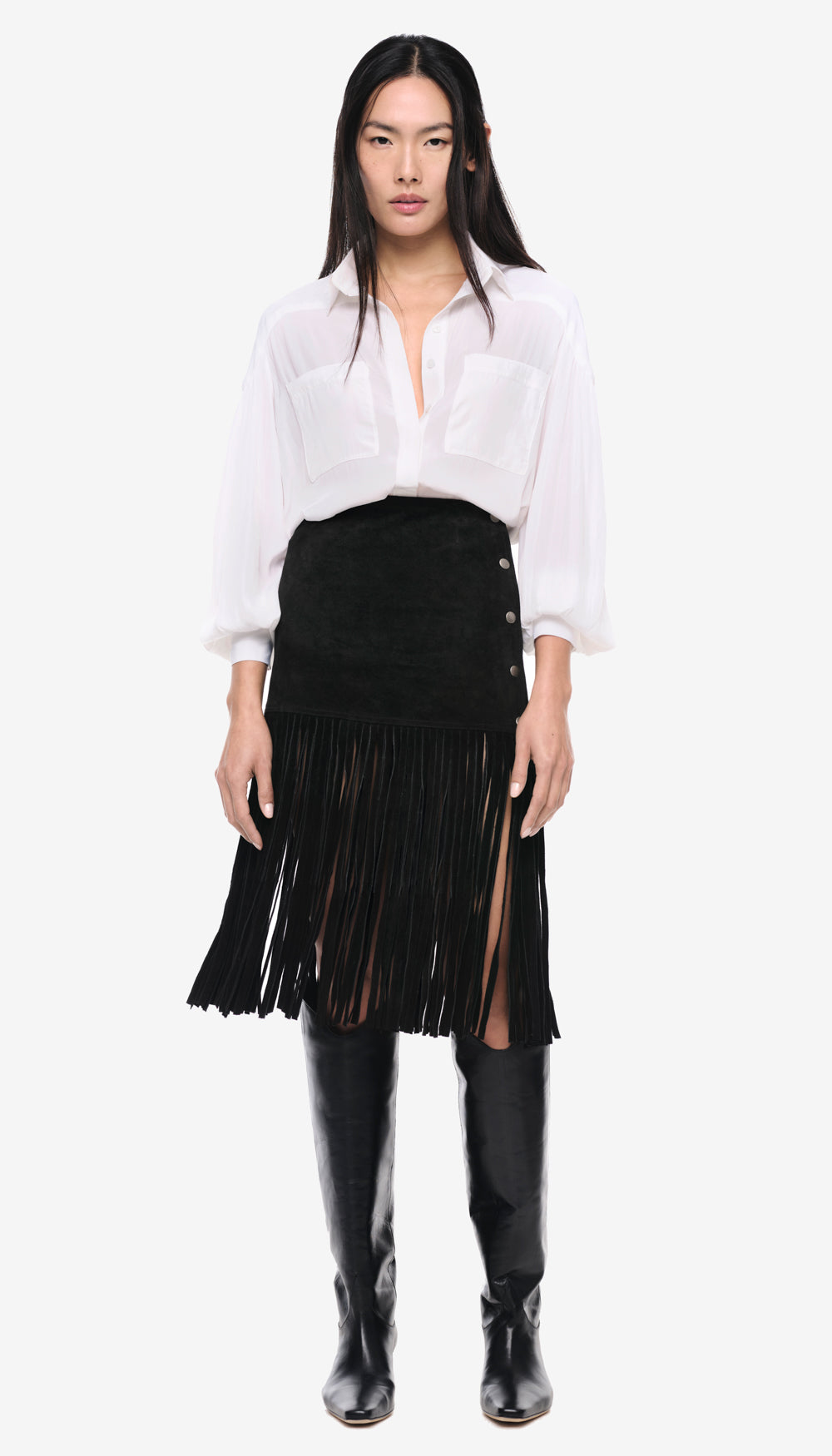 A woman in a solid white blouse and black fringe skirt.
