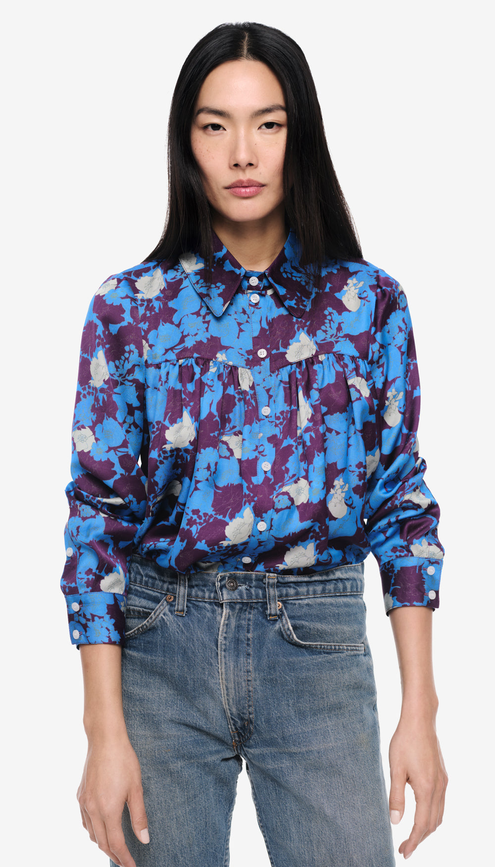 A woman in a blue and purple floral blouse.
