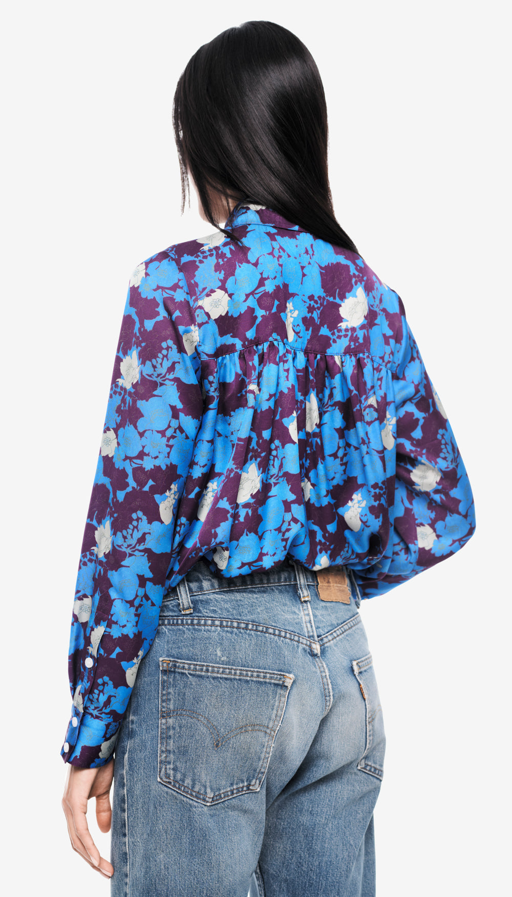 The back of a woman in a blue and purple floral blouse.
