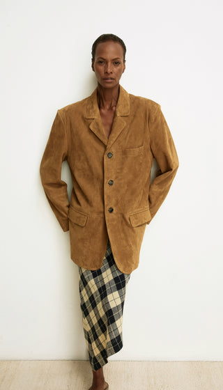 Person wearing a brown jacket and plaid skirt against a white background