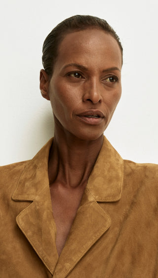 Woman wearing a brown suede jacket against a white background