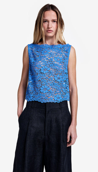 Woman wearing a blue lace top and black pants on a white background