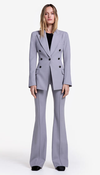 Woman wearing a gray suit with black buttons on a white background