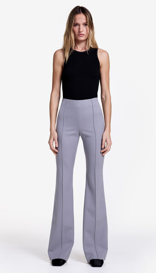 Woman wearing a black sleeveless top and gray high-waisted pants on a white background