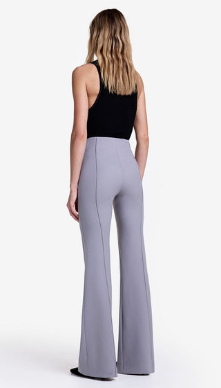Woman wearing a black top and gray wide-leg pants on a white background