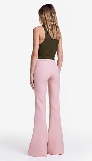 Person wearing a green sleeveless top and pink flared pants on a white background