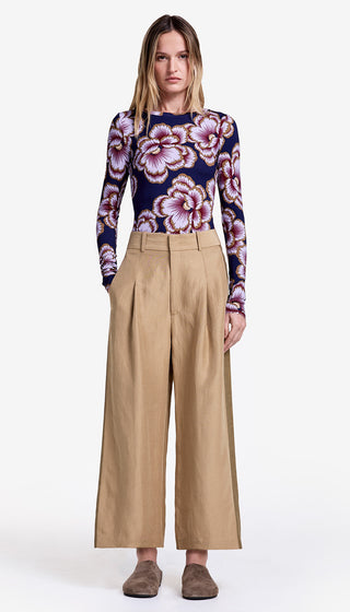 Woman wearing a floral top and beige wide-leg pants on a white background