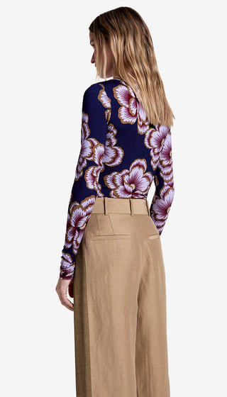 Woman wearing a floral patterned top and beige pants on a white background