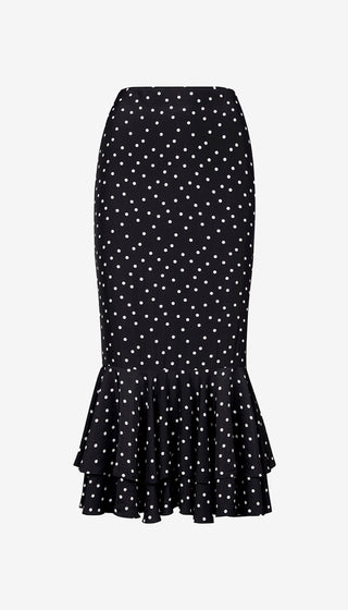 Black skirt with white polka dots and ruffled hem on a light gray background