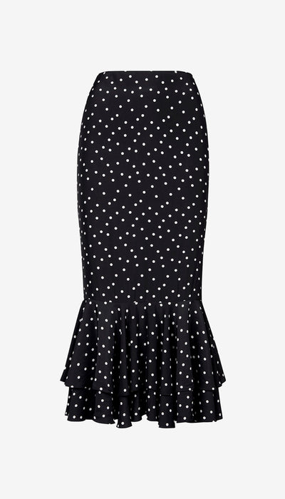 Black skirt with white polka dots and ruffled hem on a light gray background