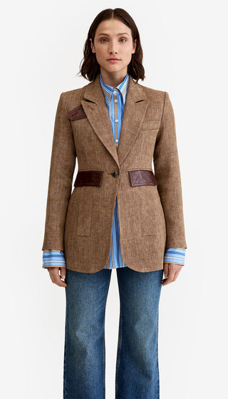 Woman wearing a brown blazer with leather patches on a white background