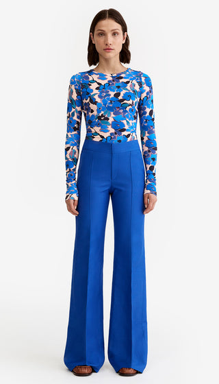 Woman wearing a blue floral top and blue pants on a white background