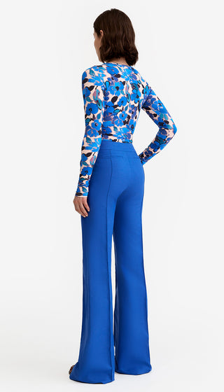 Woman wearing a blue and multicolor patterned top with wide-leg blue pants on a white background