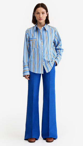 Woman wearing a blue and white striped shirt and blue flared pants on a white background