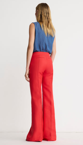 Woman wearing a blue top and red pants on a white background