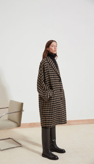 Woman wearing a patterned coat in a minimalistic setting
